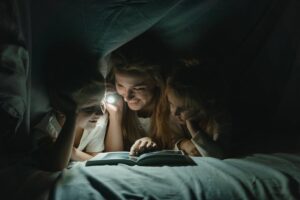 mom reading a book in a summer tent with her children
