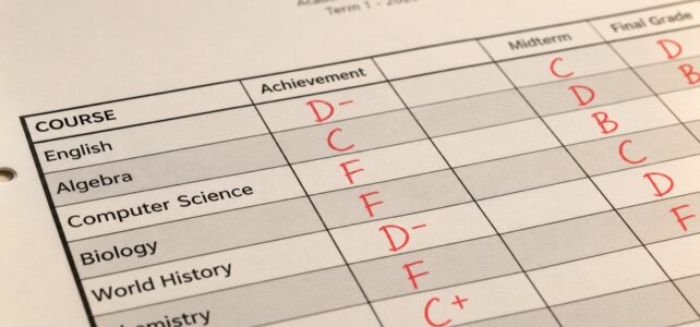 Close-up of a Westchester High School report card for 2026, showing red handwritten grades for English, Algebra, Computer Science, Biology, World History, and Chemistry on a printed table, in warm lighting.